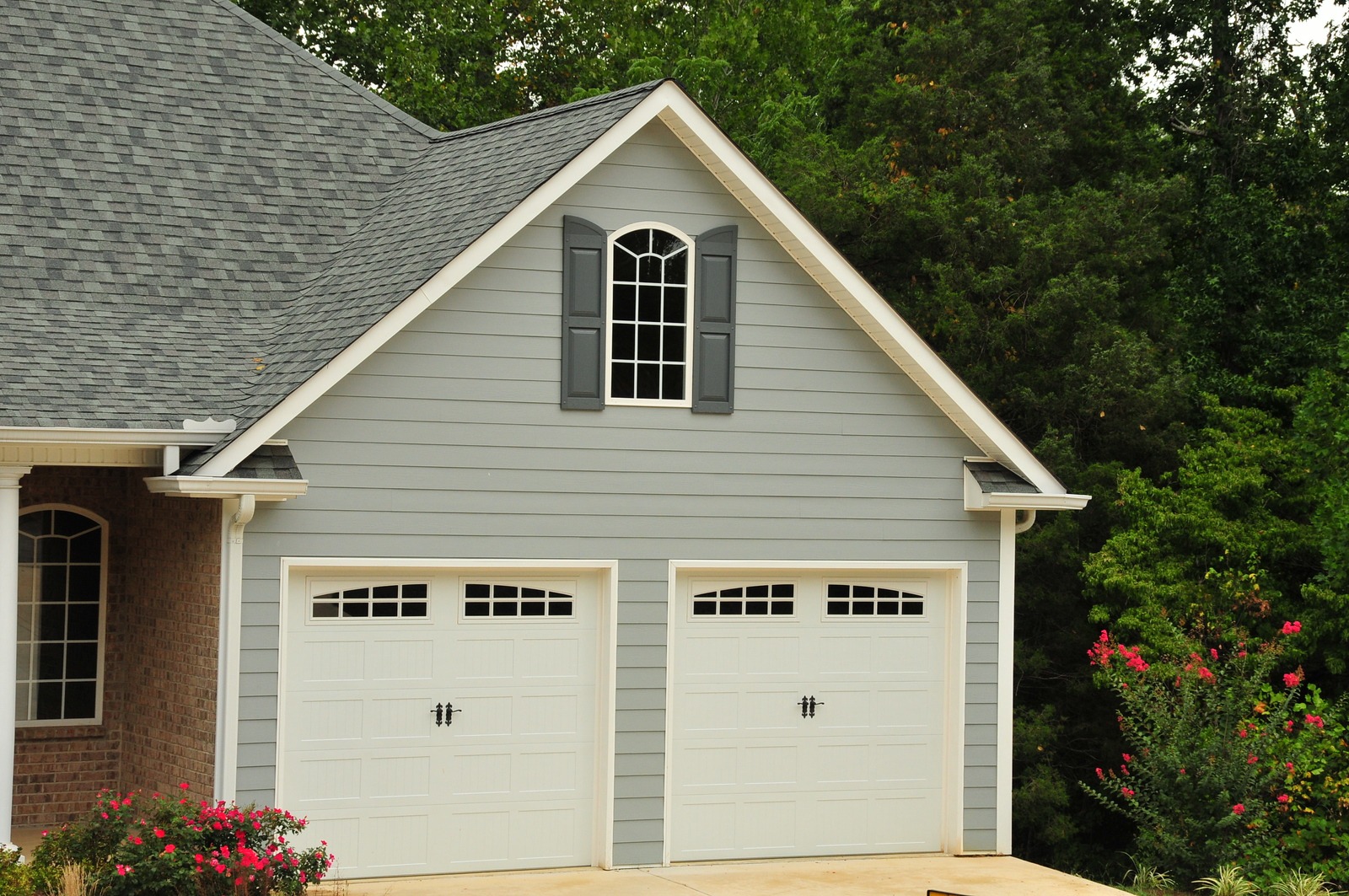 Home with white carriage garage doors with windows and black handles | local garage door company